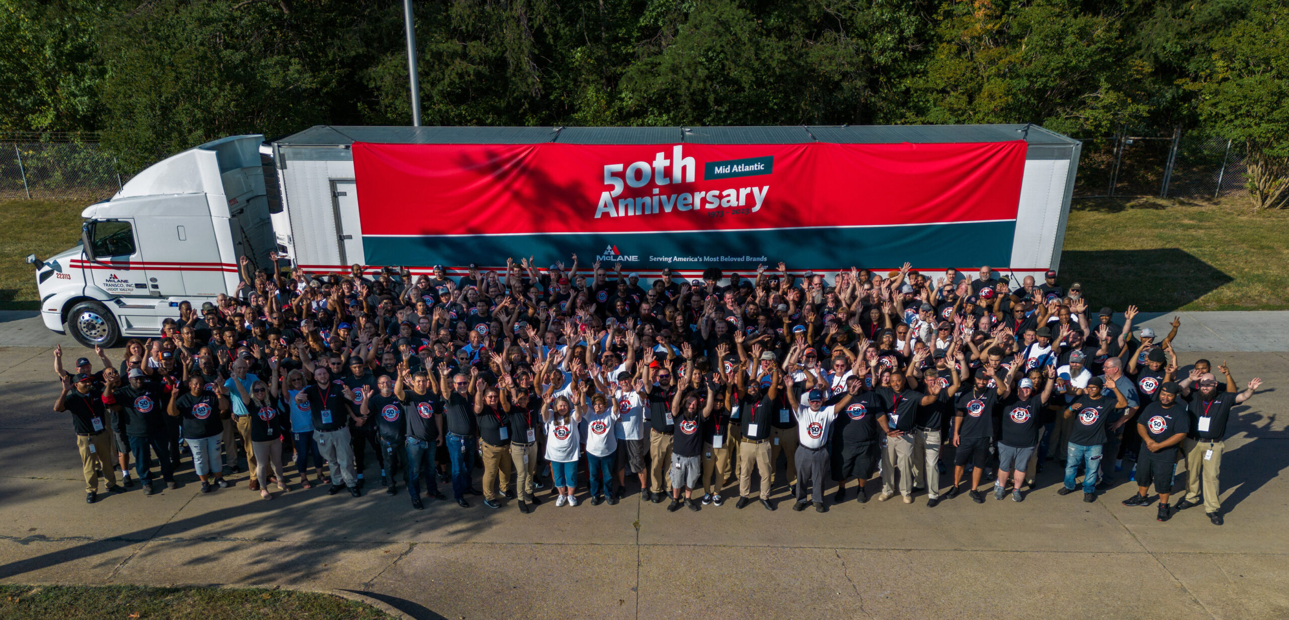 Photo of McLane Mid Atlantic teammates in front of a tractor trailer celebrating the facility's 50th anniversary.